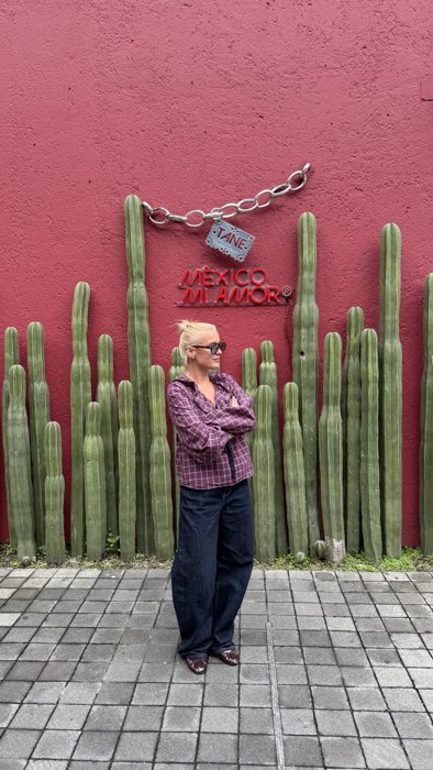 Nikoline in front of a red wall with cacti in Mexico